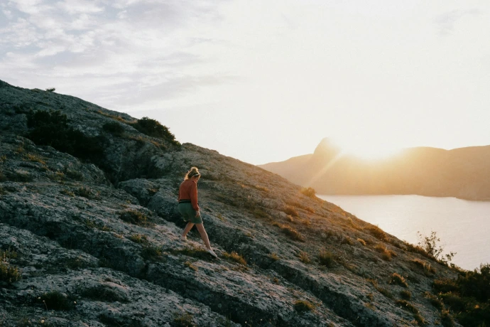 a person walking up a hill with a body of water in the background